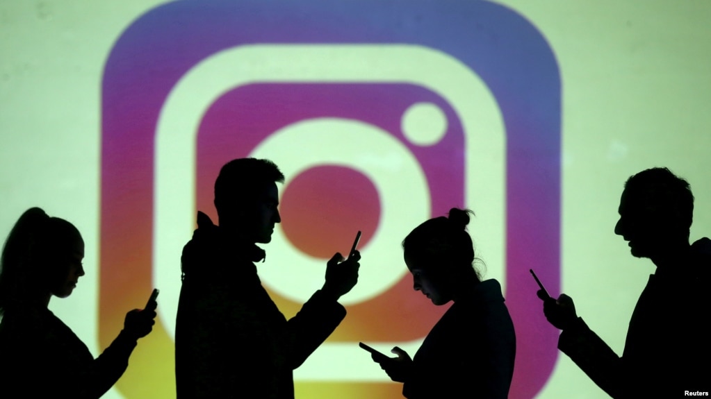 In this file photo, silhouettes of mobile users are seen next to a screen projection of the Instagram logo in this picture illustration taken March 28, 2018. (REUTERS/Dado Ruvic/Illustration/File Photo)