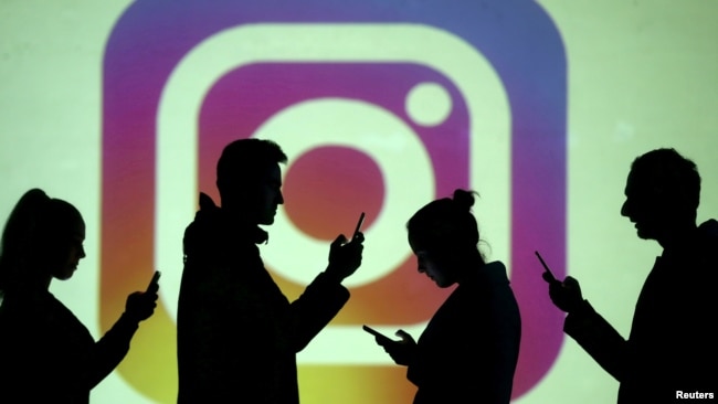 In this file photo, silhouettes of mobile users are seen next to a screen projection of the Instagram logo in this picture illustration taken March 28, 2018. (REUTERS/Dado Ruvic/Illustration/File Photo)