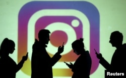 In this file photo, silhouettes of mobile users are seen next to a screen projection of the Instagram logo in this picture illustration taken March 28, 2018. (REUTERS/Dado Ruvic/Illustration/File Photo)