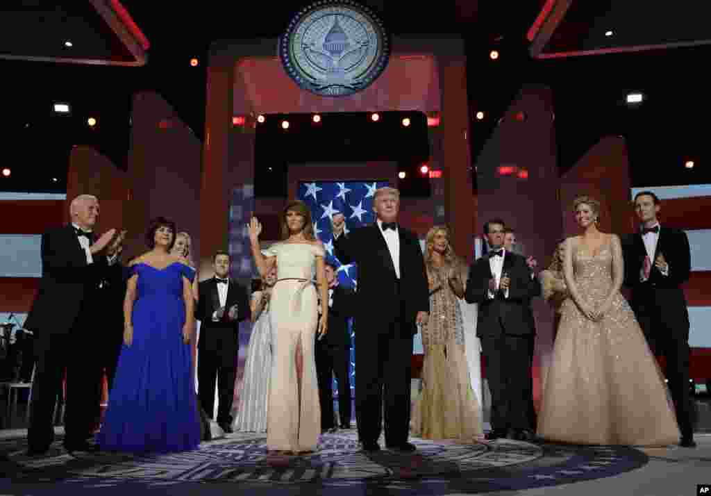 President Donald Trump acknowledges the crowd with first lady Melania Trump, Vice President Mike Pence and his wife Karen, left, and their families at the Freedom Ball, Jan. 20, 2017, in Washington. 