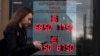 FILE - A woman walks past a currency exchange office display listing the exchange rates of U.S. dollar and euro to Russian rubles, in Moscow, Russia, March 9, 2020. 