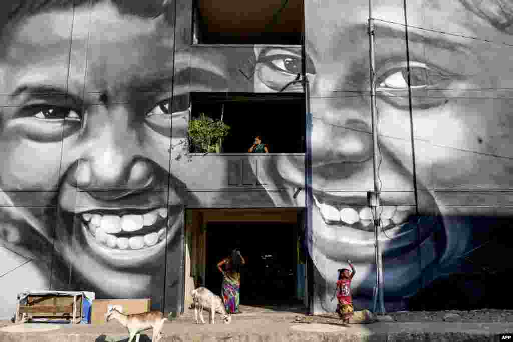 Residents walk past a mural painted on a building at a slum clearance board residential community in Chennai, India.
