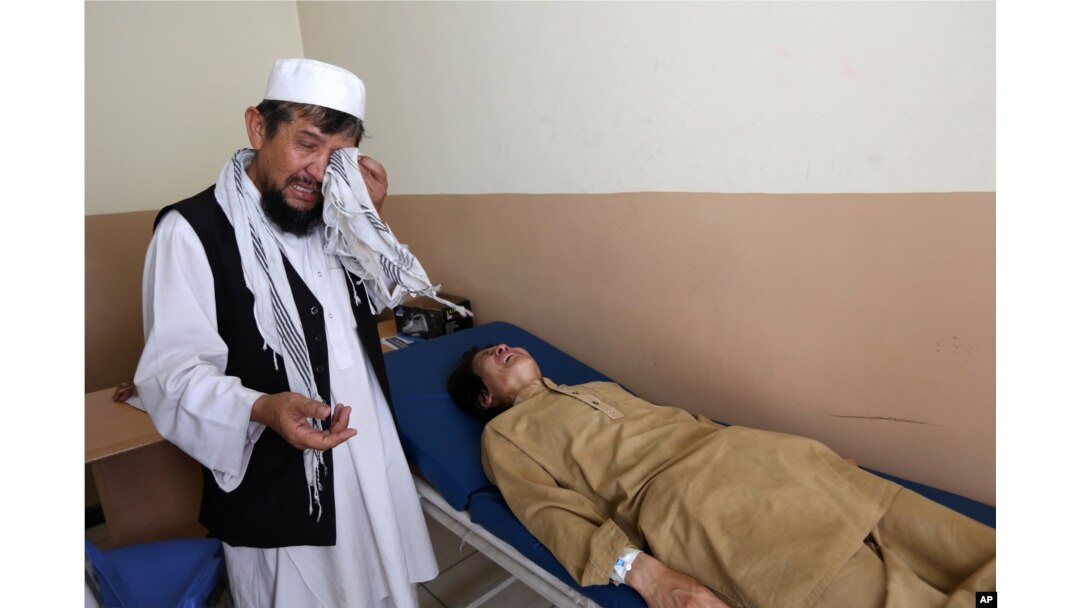 FILE - An Afghan patient is seen on the bed as a father weeps in the Mental Health and Drug Addicts' Hospital in Kabul, Afghanistan.