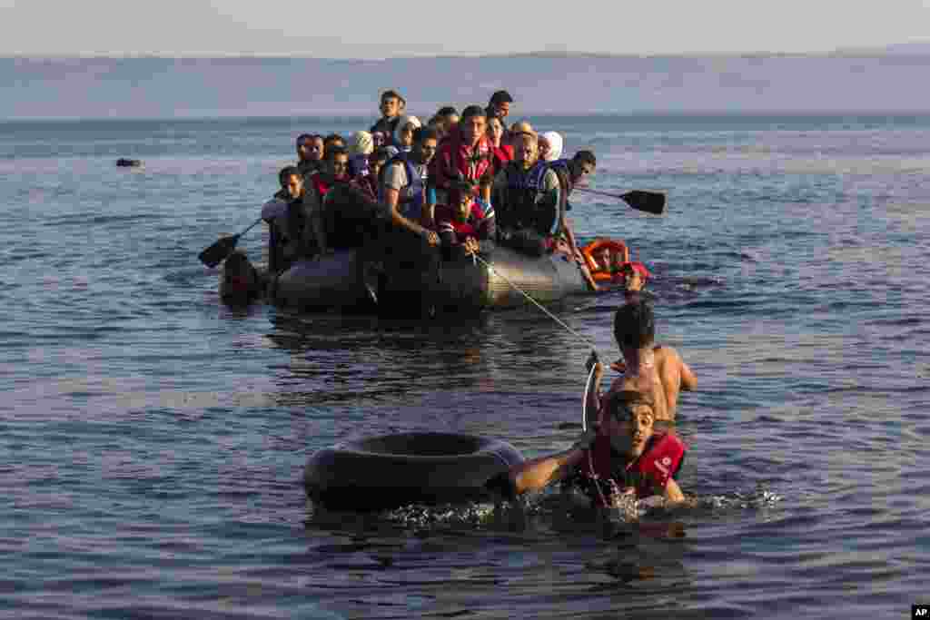 Two migrants pull an overcrowded dinghy with Syrian and Afghan refugees arriving from the Turkish coasts to the Greek island of Lesbos.