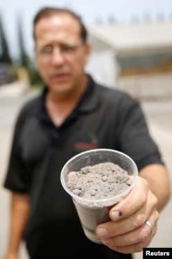 Ka'u Coffee Mill manager Lou Daniele holds a full cup of volcanic ash collected from a small lot at the mill in Pahala, Hawaii, May 25, 2018.