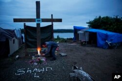 A mourner lights a candle at the memorial marking the spot where Shawn Vann Schreck died two days before in a homeless encampment where he lived along the river in Aberdeen, Wash., June 14, 2017.