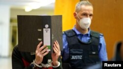 Iraqi defendant Taha al-Jumailly covers his face as he arrives before his verdict in a courtroom in Frankfurt, Germany, Nov. 30, 2021. 