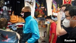 Para pelanggan dan karyawan toko baju mengenakan masker seiring dengan pelonggaran pembatasan yang diterapkan untuk mencegah penyebaran virus corona, di Houston, Texas, 1 Mei 2020. (Foto: Reuters)
