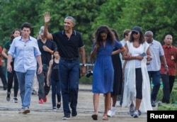 FILE - Former U.S. President Barack Obama waves while walking with his daughter Mali and his wife, Michelle, during a visit to the 9th-century Borobudur Temple in Magelang, Indonesia, June 28, 2017.