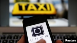 Ilustrasi aplikasi berbagi kendaraan Uber pada ponsel dan lambang taksi di Jerman. (Reuters/Kai Pfaffenbach)