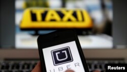 Le logo uber sur le téléphone portable et le signe d'un taxi, le 15 septembre 2014.