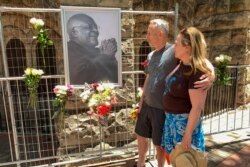 Mourners look at a portrait of South African anti-apartheid icon Desmond Tutu outside St. George's cathedral in Cape Town on Dec. 26, 2021, after the news of Tutu's passing.