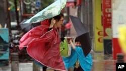 Seorang perempuan dan anaknya memegang payung mereka dengan erat, saat angin kencang yang dipicu oleh topan Usagi bergerak mendekati Taipei, Taiwan (21/9).