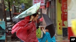 A woman and her child hold their umbrellas tight against powerful gusts of wind as Typhoon Usagi approaches in Taipei, Taiwan, Sept. 21, 2013. 