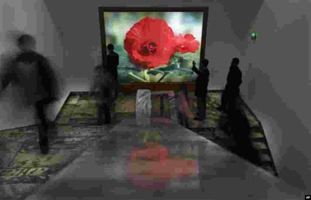 North Koreans walk past a light box featuring a Kimjongilia, a flower named after the late leader Kim Jong Il, during a flower show in Pyongyang, North Korea, Tuesday, April 17, 2012. (AP Photo/Vincent Yu)