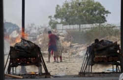 Family members of COVID-19 victims leave as their funeral pyres burn at an open crematorium set up at a granite quarry on the outskirts of Bengaluru, India, Wednesday, May 5, 2021. (AP Photo/Aijaz Rahi)