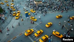 FILE - Yellow taxis pass people standing in silence during a protest at Taksim Square in Istanbul.