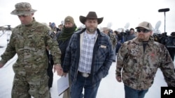Ammon Bundy, center, one of the sons of Nevada rancher Cliven Bundy, walks off after speaking with reporters during a news conference at Malheur National Wildlife Refuge headquarters, Jan. 4, 2016, near Burns, Ore.