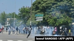 Des partisans de l'ancien président ivoirien Laurent Gbagbo affrontent la police anti-émeute à Abidjan, le 17 juin 2021, avant son arrivée dans le pays.