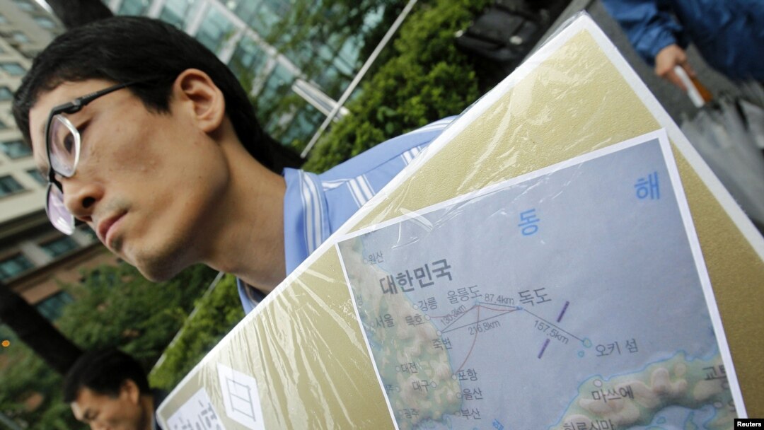 Seorang aktivis Korea Selatan menunjukkan gambar peta pulau Dokdo yang dihapus namanya dalam fitur aplikasi peta baru keluaran Apple dan Google (foto: dok).