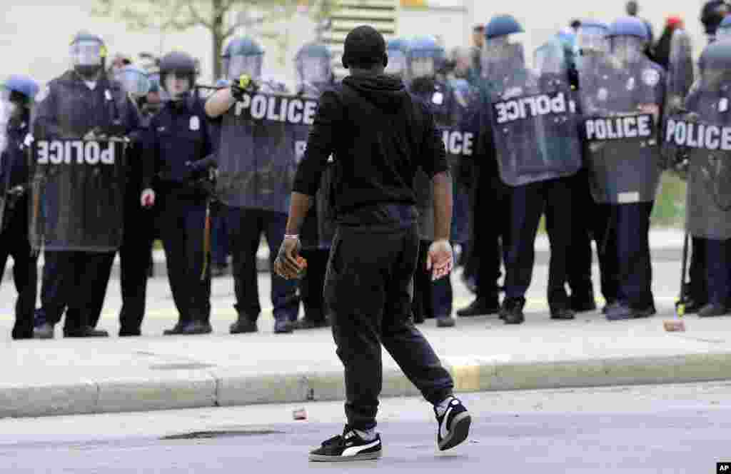 Nümayişçi polisin yanı ilə əlində kərpic keçir.&nbsp; Baltimor. 27 aprel, 2015.