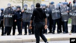 Un manifestant marchant devant les policiers, après les funérailles de Freddie Gray à Baltimore, le 27 avril 2015.