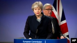 European Commission President Jean-Claude Juncker, right, walks behind British Prime Minister Theresa May prior to addressing a media conference at EU headquarters in Brussels, Dec. 4, 2017.