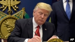 FILE - President Donald Trump signs an executive order on extreme vetting during an event at the Pentagon in Washington, Jan. 27, 2017.