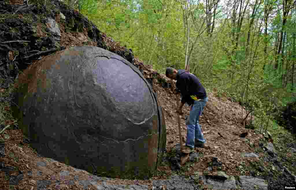 Suad Keserovic membersihkan batu raksasa berbentuk bola (dengan diameter 3,3 meter) yang menjadi atraksi turis di desa Podubravlje, dekat Zavidovici, Bosnia dan Herzegovina.