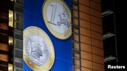 A banner showing a Latvian Euro coin is seen on the facade of the European Commission headquarters during a European Union leaders summit in Brussels December 20, 2013. Latvia will join the euro zone on Jan. 1, 2014. 