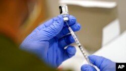 FILE - A health care worker fills a syringe with the Pfizer COVID-19 vaccine at Jackson Memorial Hospital, in Miami, Oct. 5, 2021. 