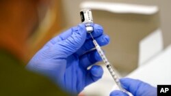 FILE - A health care worker fills a syringe with the Pfizer COVID-19 vaccine at Jackson Memorial Hospital, in Miami, Oct. 5, 2021. 