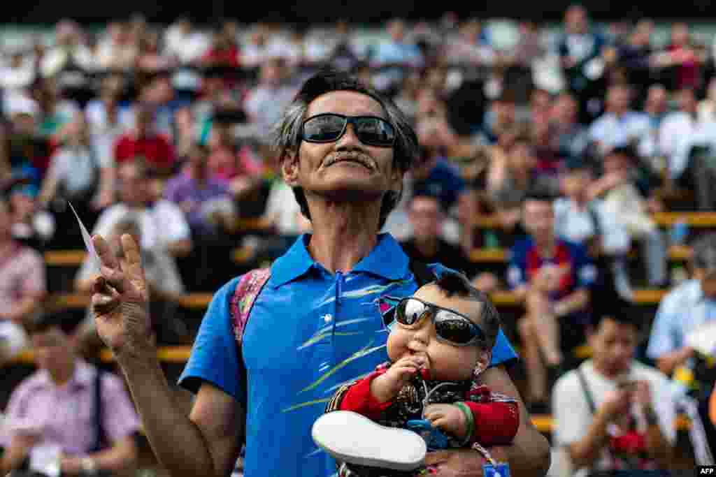 A man holds a baby doll during the horse race opening at the Sha Tin Racecourse of the Hong Kong Jockey Club.