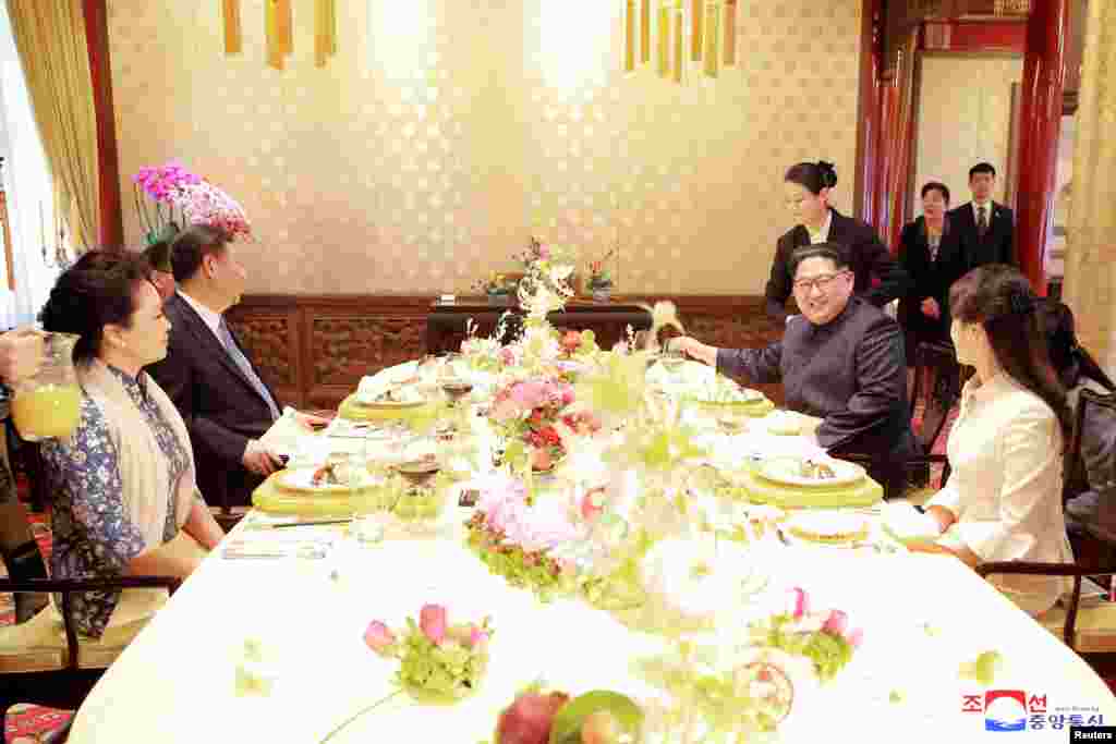 Kuzey Kore lideri Kim Jong Un, eşi Ri Sol Ju, Çin lideri Xi Jinping ve eşi Peng Liyuan&#39;la birlikte yemek masasında. Fotoğrafı Kuzey Kore&#39;nin Kore Merkezi Haber Ajansı görüntülemiş. Fotoğrafın hangi gün çekildiği bilinmiyor.