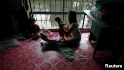 FILE - Aey, a 20-year old mother of three, holds her son at their home in a Bangkok's slum October 7, 2012. 