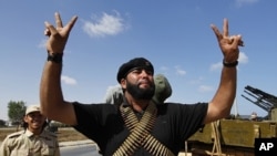 A member of the forces loyal to Libya's interim rulers flashes the victory sign as he prepares for an assault on Muammar Gaddafi's hometown Sirte September 24, 2011.