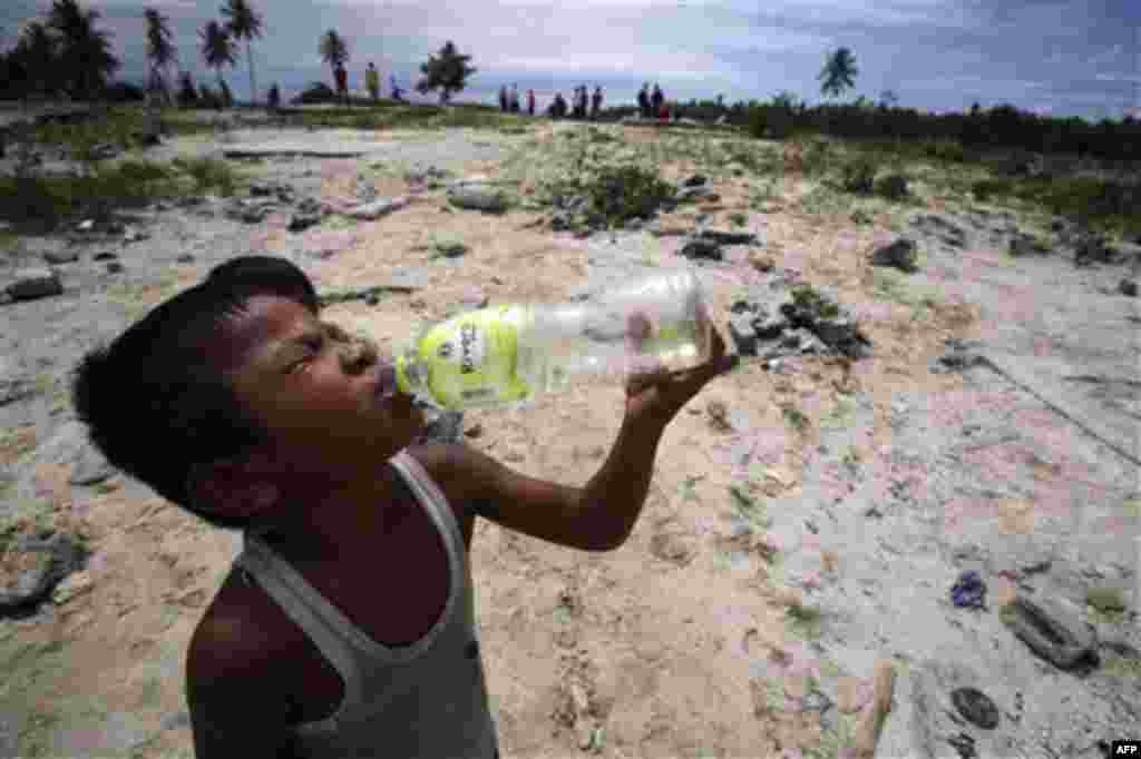 A boy tsunami survivor drinks water at an area affected by Monday's earthquake-triggered tsunami at Parorogat village, Pagai island, West Sumatra, Indonesia, on Thursday, Oct. 28, 2010. (AP Photo/Achmad Ibrahim)