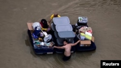 Residents wade with their belongings through flood waters brought by Tropical Storm Harvey in Northwest Houston, Texas, Aug. 30, 2017. 