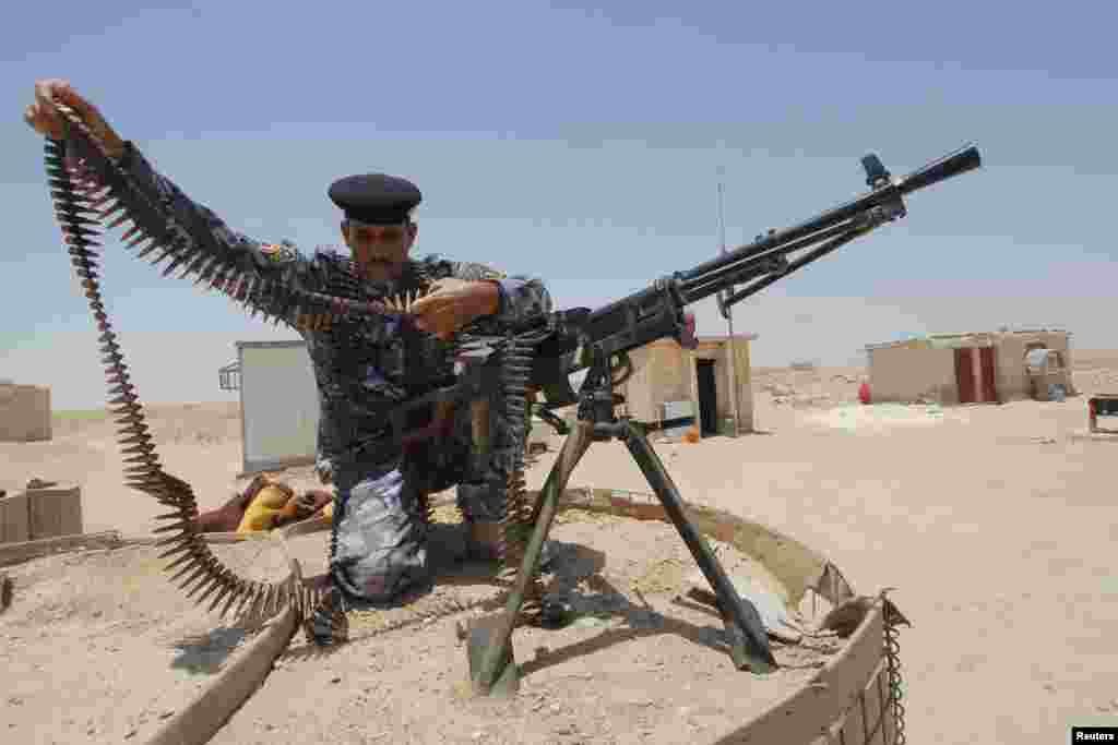 A member of the Iraqi security forces works with an ammunition belt near a weapon in the desert region between Kerbala and Najaf, south of Baghdad, June 28, 2014