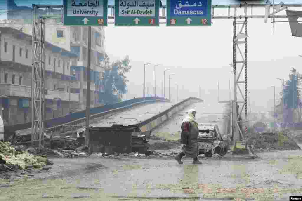 A man crosses the Al-Haj highway, which is closed because of sniper fire by forces loyal to Syria's President Bashar Al-Assad, in Aleppo.