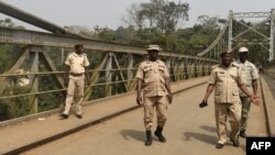 Les agents d'immigration marchent sur un pont suspendu construit en 1948 qui relie le Nigéria au Cameroun à la gare frontalière de Mfum, dans l'État de Cross Rivers, au sud-est du Nigeria, le 1er février 2018.