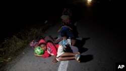 Jason, 11, sleeps using a toy ball as pillow during a break from walking early morning on the road that connects Pijijiapan with Arriaga, Mexico, Oct. 26, 2018. After a downpour, his family had tossed everything they had packed from home because the items were too wet to carry, but people along their route gave them new clothes, backpacks, strollers, and more. Father Joel Eduardo Espinar said it felt like they were being carried along by a wave of kindness and generosity.