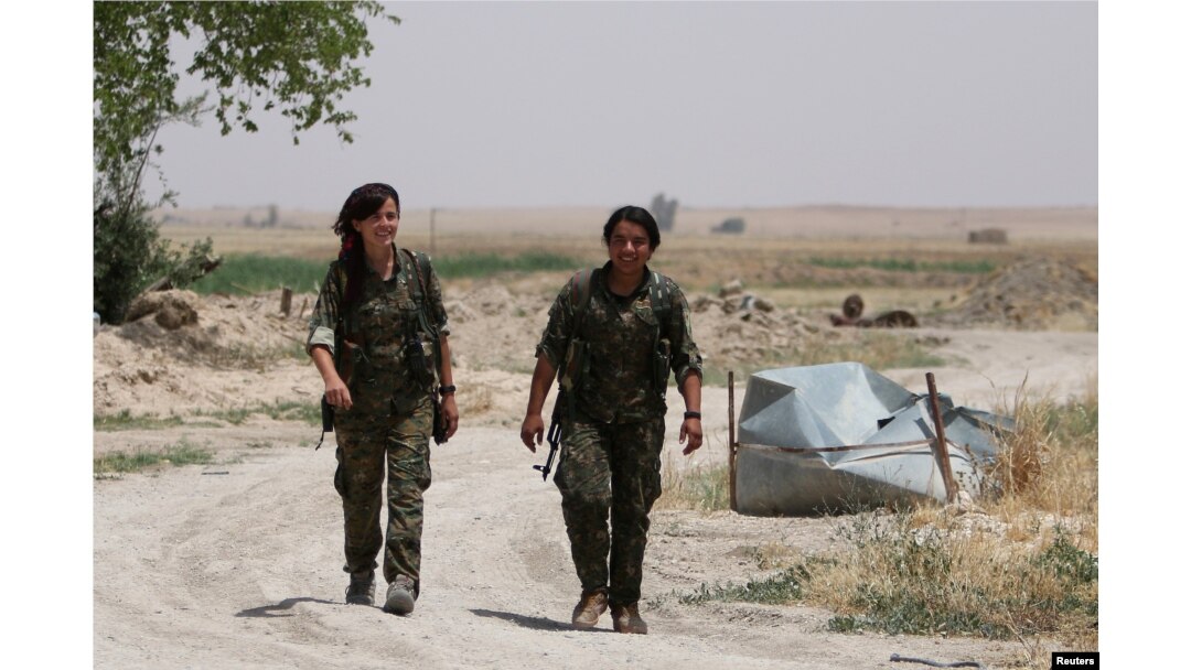 FILE - Kurdish female fighters from the People's Protection Units (YPG), operating alongside with the Syria Democratic Forces, walk in northern province of Raqqa, Syria, May 27, 2016.