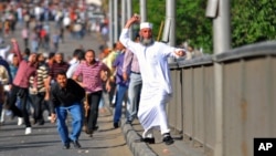 Man throws a stone during clashes between rival groups of protesters in Cairo, Egypt, Friday, April 19, 2013.
