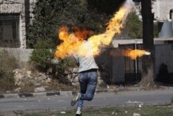 Seorang pengunjuk rasa Palestina melemparkan bom molotov ke pasukan Israel selama bentrokan di kota Hebron, Tepi Barat. (Foto: REUTERS/Mussa Qawasma)