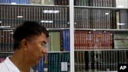 A Chinese man walks by a cabinets displaying Chinese encyclopedias at a book store in Beijing, May 4, 2017.
