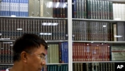 A Chinese man walks by a cabinets displaying Chinese encyclopedias at a book store in Beijing, May 4, 2017.