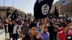 FILE - Young men chant pro-Islamic State slogans as they wave the group's flags in Mosul, Iraq.