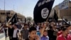 FILE - Young men chant pro-Islamic State slogans as they wave the group's flags in Mosul, Iraq.