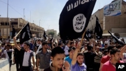 FILE - Young men chant pro-Islamic State slogans as they wave the group's flags in Mosul, Iraq.